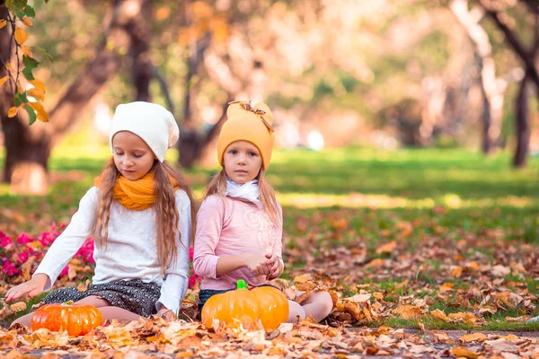 Μικρά αξιολάτρευτα κορίτσια με κολοκύθα έξω σε μια ζεστή μέρα του φθινοπώρου. — Φωτογραφία Αρχείου