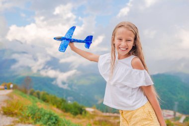 Oyuncak uçağıyla dağlarda gezen mutlu küçük kız