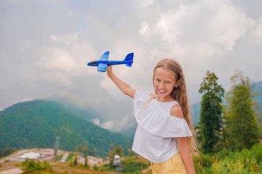 Oyuncak uçağıyla dağlarda gezen mutlu küçük kız
