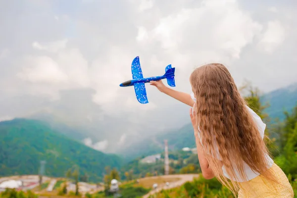 Szczęśliwa dziewczynka z samolotem zabawki w rękach w górach — Zdjęcie stockowe