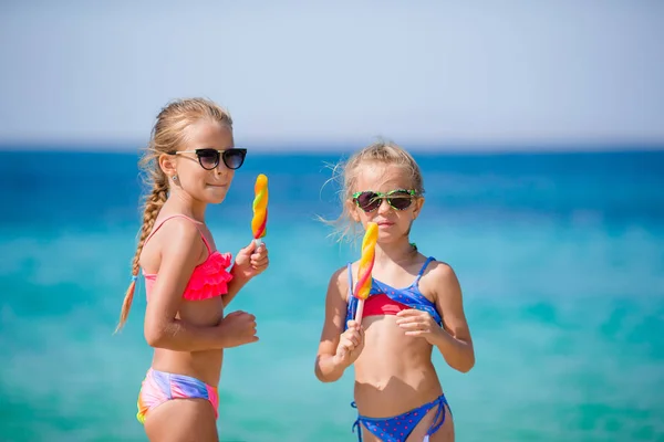 Szczęśliwe dziewczynki jedzące lody podczas wakacji na plaży. Ludzie, dzieci, przyjaciele i koncepcja przyjaźni — Zdjęcie stockowe