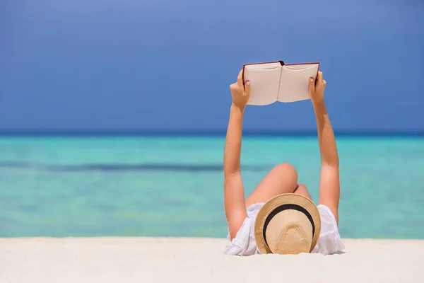 Portret van een jonge vrouw ontspannen op het strand, het lezen van een boek — Stockfoto