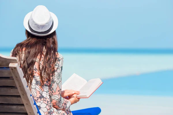 Retrato de uma jovem mulher relaxando na praia, lendo um livro — Fotografia de Stock