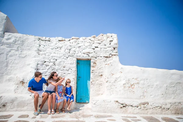 Family vacation in Europe. Parents and kids at street of typical greek traditional village with white walls and colorful doors on Mykonos Island — Stock Photo, Image