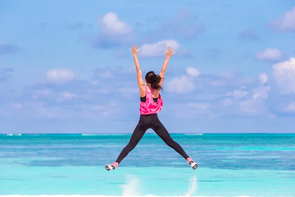 Fit young woman doing exercises on tropical white beach in her sportswear — Stock Photo, Image