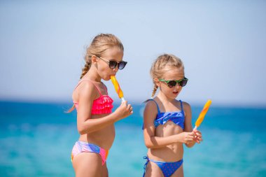 Plaj tatili sırasında dondurma yiyen mutlu küçük kızlar..