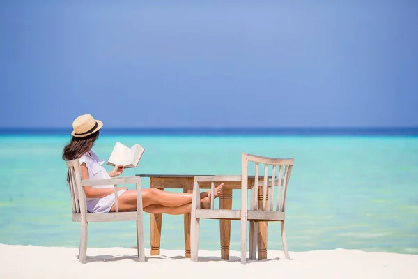 Giovane donna che legge al bar sulla spiaggia all'aperto — Foto Stock