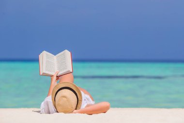 Sahilde dinlenen, kitap okuyan genç bir kadının portresi