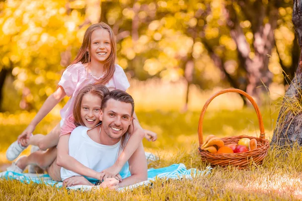 Счастливый отец и маленькие дочери отдыхают у озера — стоковое фото