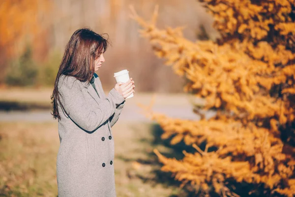 Höstkoncept - vacker kvinna dricker kaffe i höstparken under höstlövverk — Stockfoto