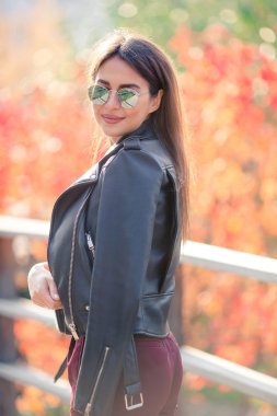 Sonbahar konsepti: Sonbahar parkında sonbahar yaprakları altında kahve içen güzel bir kadın.