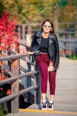 Sonbahar konsepti: Sonbahar parkında sonbahar yaprakları altında kahve içen güzel bir kadın.