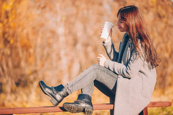 Conceito de queda - bela mulher bebendo café no parque de outono sob folhagem de outono — Fotografia de Stock