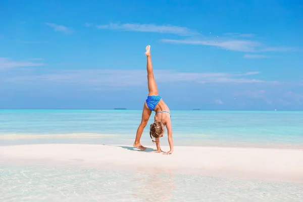 Schattig klein meisje met plezier radslag maken op tropisch wit zandstrand — Stockfoto