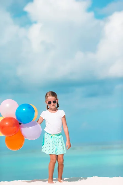 Очаровательная маленькая девочка играет с воздушными шарами на пляже — стоковое фото