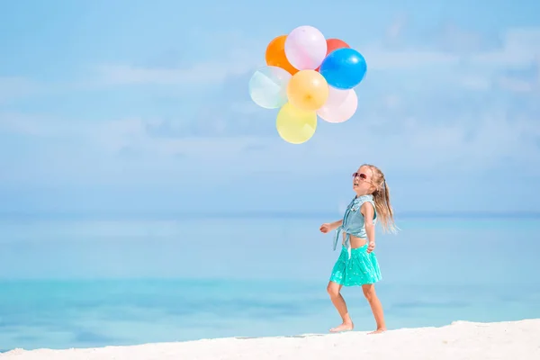 Adorável menina brincando com balões na praia — Fotografia de Stock