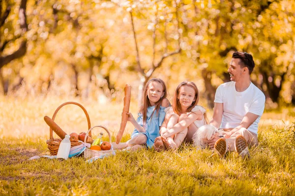 Feliz padre y las pequeñas hijas se relajan junto al lago — Foto de Stock