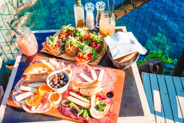 Gustoso spuntino italiano. Bruschette fresche, formaggi e carne in tavola in caffetteria con vista a Manarola — Foto Stock