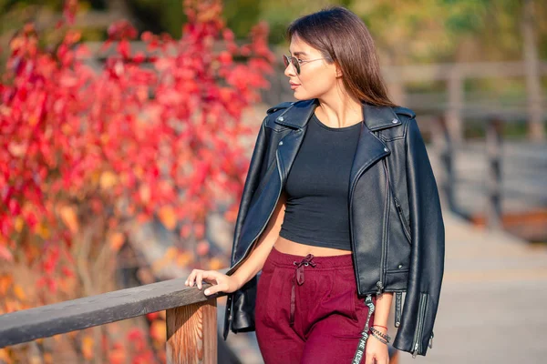 El concepto de otoño - la mujer hermosa que bebe café en el parque otoñal bajo el follaje otoñal — Foto de Stock