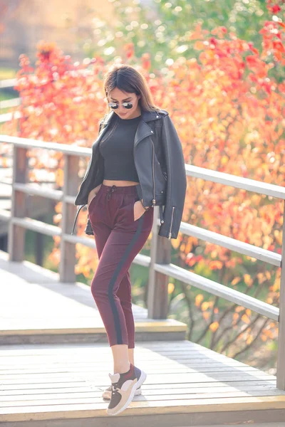 El concepto de otoño - la mujer hermosa que bebe café en el parque otoñal bajo el follaje otoñal — Foto de Stock