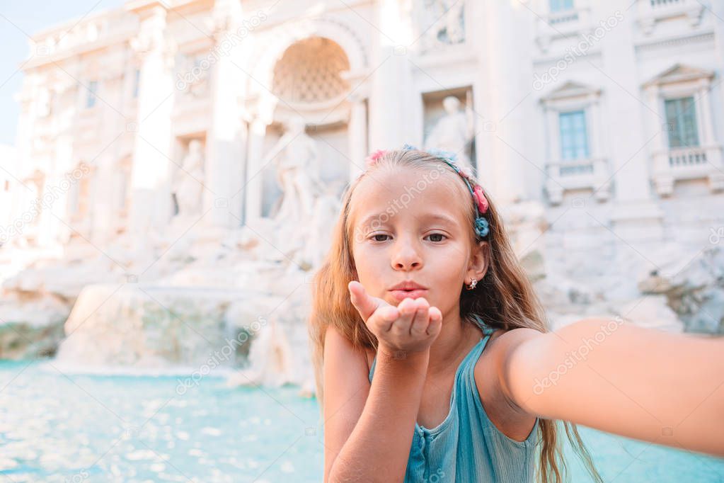 Adorable little girl taking selfie by the Fountain of Trevi in Rome.