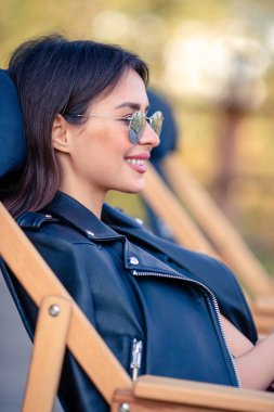 Sonbahar konsepti: Sonbahar parkında sonbahar yaprakları altında kahve içen güzel bir kadın.