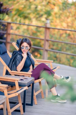 Sonbahar konsepti: Sonbahar parkında sonbahar yaprakları altında kahve içen güzel bir kadın.