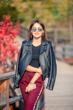 Sonbahar konsepti: Sonbahar parkında sonbahar yaprakları altında kahve içen güzel bir kadın.