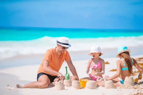 Otec a malé dcery, takže hrad z písku na tropické pláži — Stock fotografie