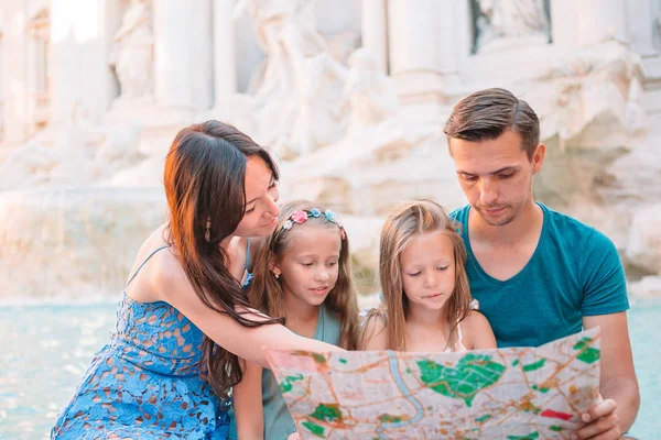 Familia feliz cerca de Fontana di Trevi con mapa de la ciudad — Foto de Stock