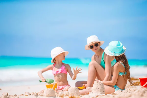 Mãe e filhas fazendo castelo de areia na praia tropical — Fotografia de Stock