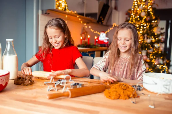 Niñas haciendo casa de jengibre de Navidad en la chimenea en la sala de estar decorada. — Foto de Stock