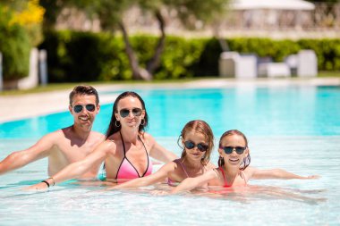 İki çocuklu genç aile keyfini çıkarın tatil yaz Açık Yüzme havuzunda