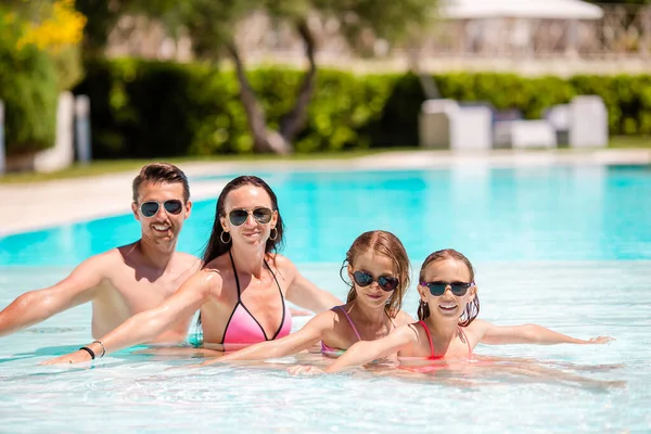 Młode rodziny z dwójką dzieci korzystać z wakacji w basenie — Zdjęcie stockowe