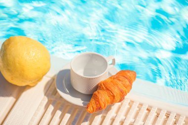 Lezzetli kahvaltı limonu, kahve, havuz kenarında kruvasan.