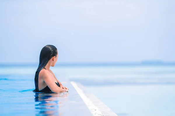 Young beautiful woman enjoying the luxurious quiet swimming pool — Stock Photo, Image