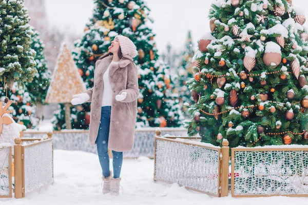 Gelukkig meisje in de buurt van dennenboom tak in de sneeuw voor het nieuwe jaar. — Stockfoto