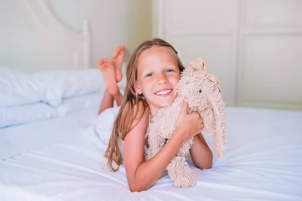 Маленькая девочка со своим игрушечным кроликом смотрит в камеру — стоковое фото