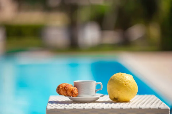 Heerlijk ontbijt citroen, koffie, croissant bij het zwembad — Stockfoto