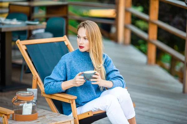 Herbstkonzept - schöne Frau trinkt Kaffee im Herbstpark unter Herbstlaub — Stockfoto