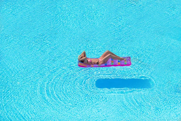 Jonge vrouw in bikini luchtmatras in het grote zwembad — Stockfoto