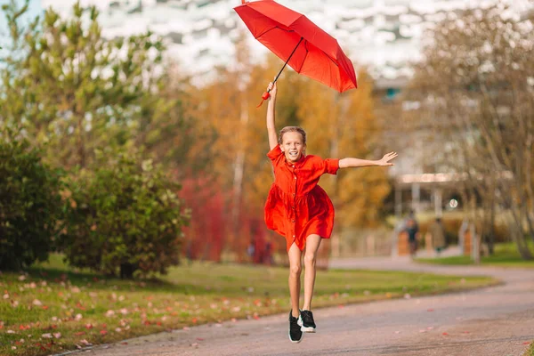 Feliz niña se ríe bajo paraguas rojo —  Fotos de Stock