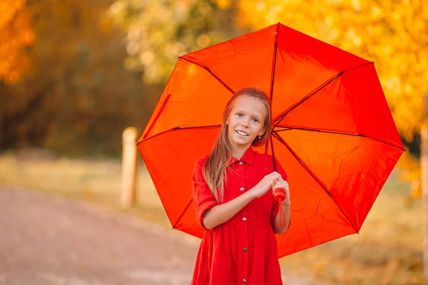 Lycklig barn flicka skrattar under rött paraply — Stockfoto