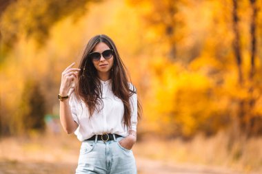 Sonbahar konsepti: Sonbahar parkında sonbahar yeşilliği altında güzel bir kadın.