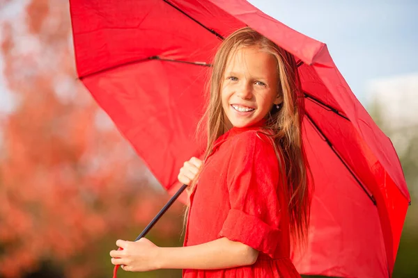 Ragazza felice bambino ride sotto ombrello rosso — Foto Stock