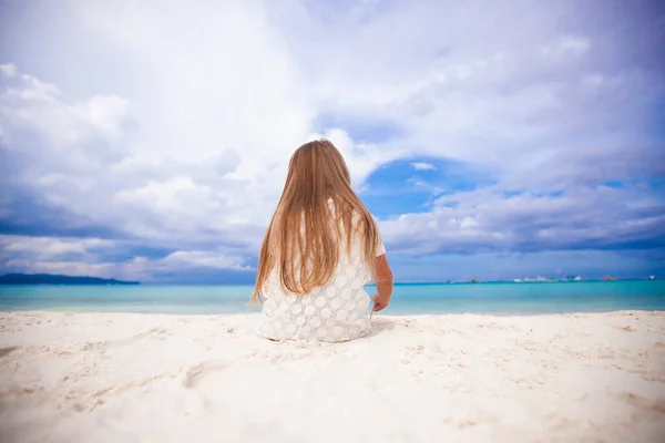 Vista trasera de la niña linda siiting en la playa — Foto de Stock