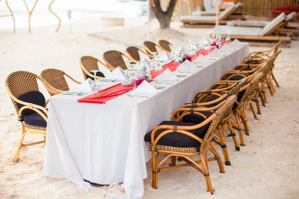 Mesa al aire libre vacía de verano para banquetes en la playa al atardecer —  Fotos de Stock