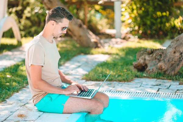 Mladý muž s laptopem v bazénu. — Stock fotografie