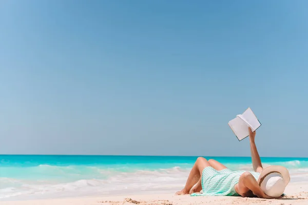 Νεαρή γυναίκα διαβάζοντας το βιβλίο στην ξαπλώστρα στην παραλία — Φωτογραφία Αρχείου