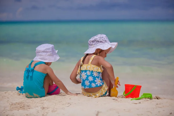 Achteraanzicht van twee kleine zusters in mooie zwemkleding spelen op zandstrand — Stockfoto